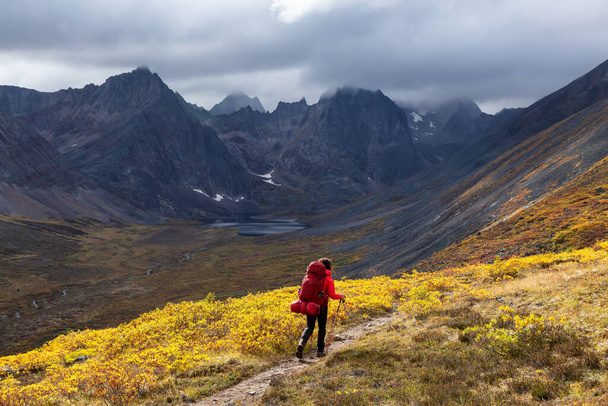 Mochilero mujer en sendero panorámico rodeado de montañas resistentes - Foto, Imagen