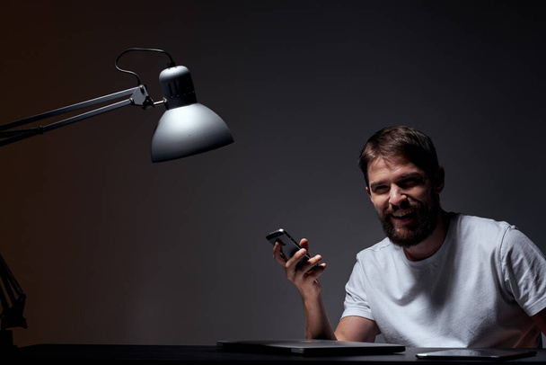 business man with mobile phone on dark background and iron lamp cropped view of work - Photo, image