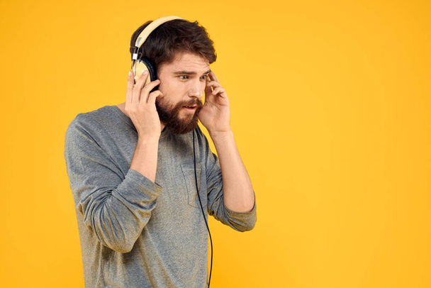 Człowiek w słuchawkach słucha technologii muzycznej styl życia zabawy ludzie żółty tło - Zdjęcie, obraz