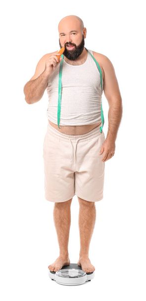 Hombre con sobrepeso parado en escamas sobre fondo blanco. Concepto de pérdida de peso - Foto, imagen