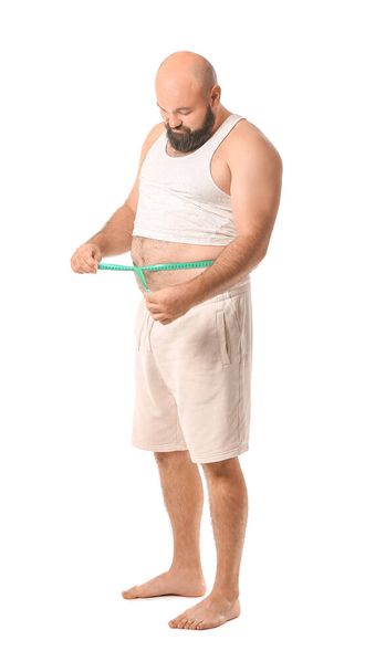 Muž s nadváhou a měřicí páskou na bílém pozadí. Koncept hubnutí - Fotografie, Obrázek