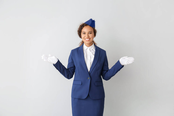 Beautiful African-American stewardess on grey background - Foto, afbeelding