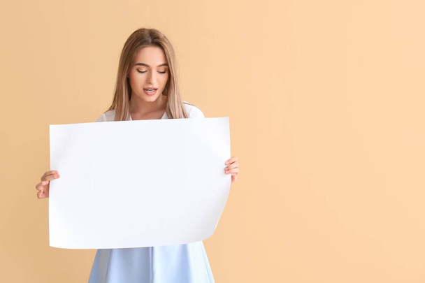 Young woman with blank paper sheet on color background - Photo, Image