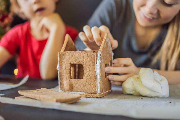 Young mother and kid making gingerbread house on Christmas eve - Foto, Imagem