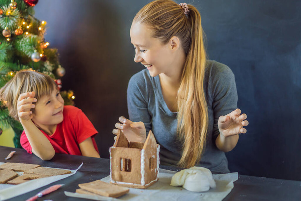 Young mother and kid making gingerbread house on Christmas eve - Foto, Imagen