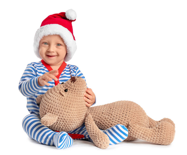 Beyaz arka planda oyuncağı olan Noel Baba şapkalı şirin bir bebek. - Fotoğraf, Görsel