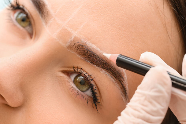 Young woman undergoing eyebrow correction procedure in beauty salon, closeup - Photo, Image