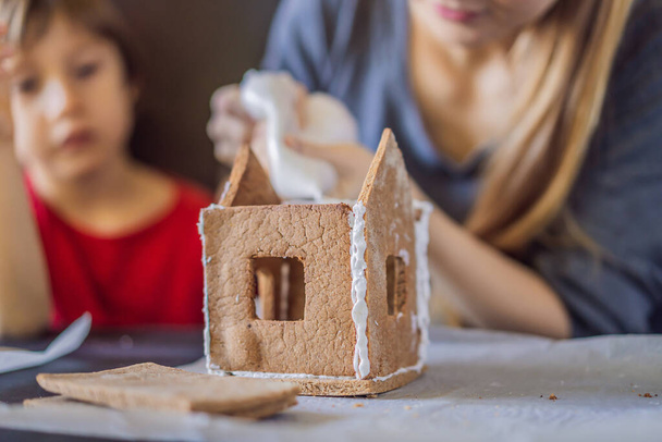 Young mother and kid making gingerbread house on Christmas eve - Foto, Imagen