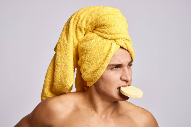 Handsome man with cosmetology facial sponge and yellow towel on his head - Φωτογραφία, εικόνα