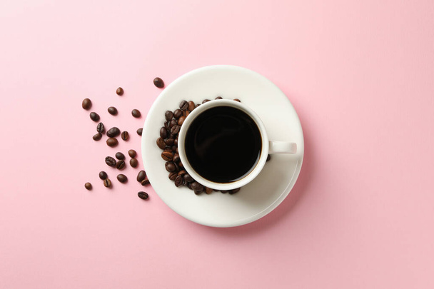 Pembe arka planda bir fincan kahve ve fasulye - Fotoğraf, Görsel
