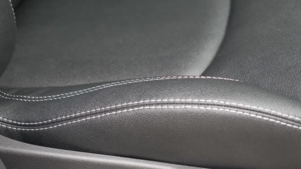 Piękne czarne skórzane pokrowce we wnętrzu samochodu. Modny nowy projekt. Schludne, piękne szwy na przednim siedzeniu. Sztuczna skóra. Zbliżenie - Materiał filmowy, wideo