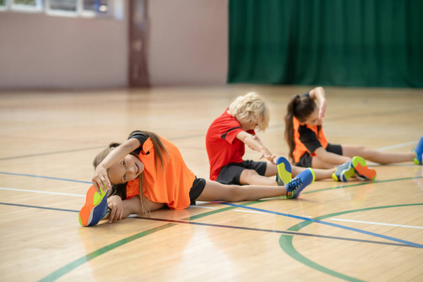 Three kids sitting on the floor and stretching - 写真・画像