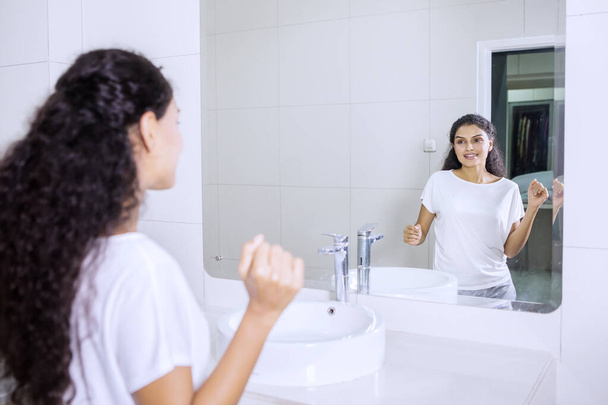 Portrait of Indian young woman dancing in front of mirror after brushing teeth in the bathroom - Foto, immagini