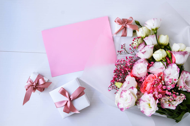 card mockup with delicate bouquet and gift boxes. floral background. Top view Flat lay Holiday card 8 March, Happy Valentine's day, Mother's day concept. Copy space for text. Holiday greeting card - Fotó, kép