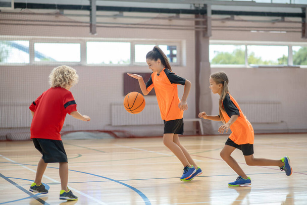 Kids in bright sportswear playing basketball together and feeling involved - Fotoğraf, Görsel