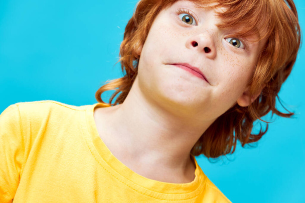 Cheerful red-haired boy with a surprised look close-up yellow T-shirt - Foto, Imagen