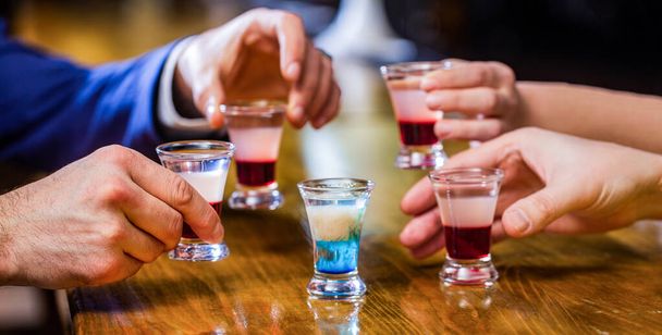 Male hands glasses of shot or liqueur. Friends drink shot or liqueur. Five glasses of alcohol.Tequila shots, vodka, whisky, rum - Photo, Image