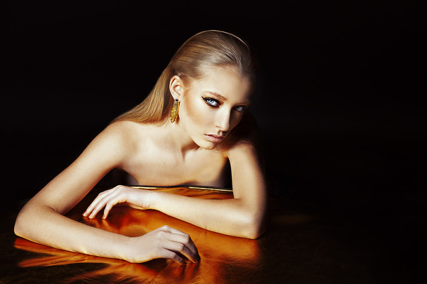 Beautiful high fashion model with gold earrings made in studio. - Photo, Image