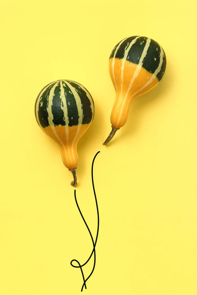 Yellow-green pumpkins in the form of a balloons with ropes on a yellow background. - Foto, immagini