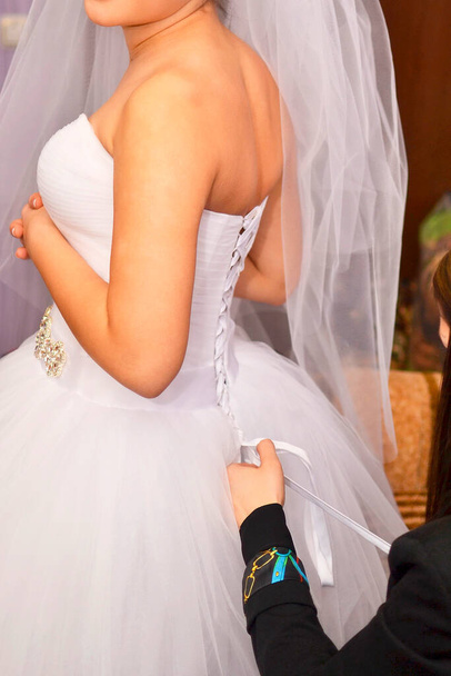 ženské ruce svázané stuhami na zadní straně svatební šaty nevěsty - Fotografie, Obrázek