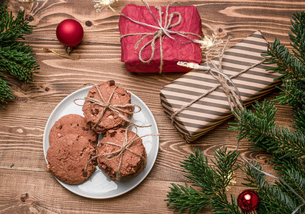 Cookies, gift boxes and a spruce branch on a wooden table. View from above. - Photo, image