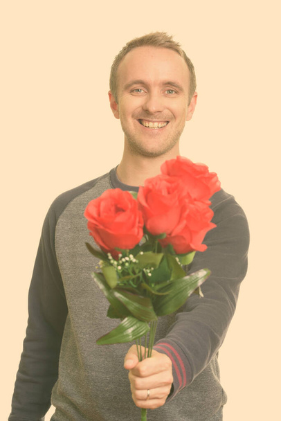 Szczęśliwy przystojny biały mężczyzna daje czerwone róże gotowe na Walentynki - Zdjęcie, obraz