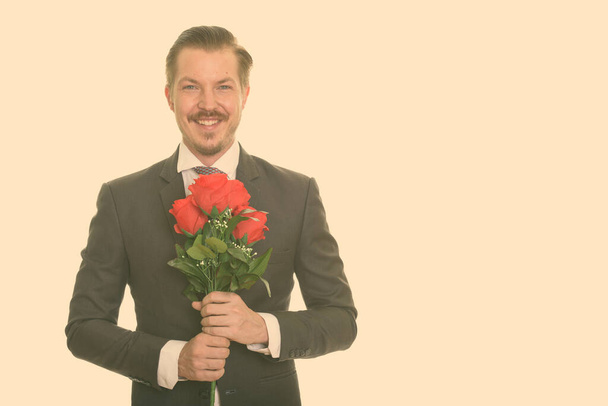 Щасливий кавказький бізнесмен, який тримає червоні троянди готові до дня святого Валентина. - Фото, зображення