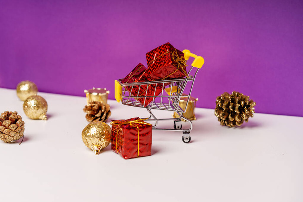 Az újévi ünnepi eladások koncepciója. Mini kosár ajándékokkal a lila háttér szétszórt karácsonyi dekorációk körül - Fotó, kép