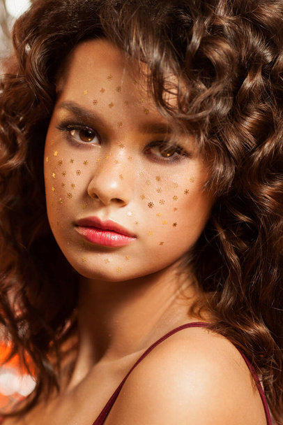Creative winter makeup with golden snowflakes on her face and wavy hairstyle - 写真・画像