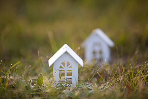 Figures of small white wooden houses on the grass close-up. The cottage is in a rural location and village, building, project, moving , mortgage, rent and purchase real estate. Copy space - Fotografie, Obrázek