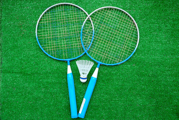 Two badminton mini rackets with white shuttlecock on the green background, active games. - Фото, изображение