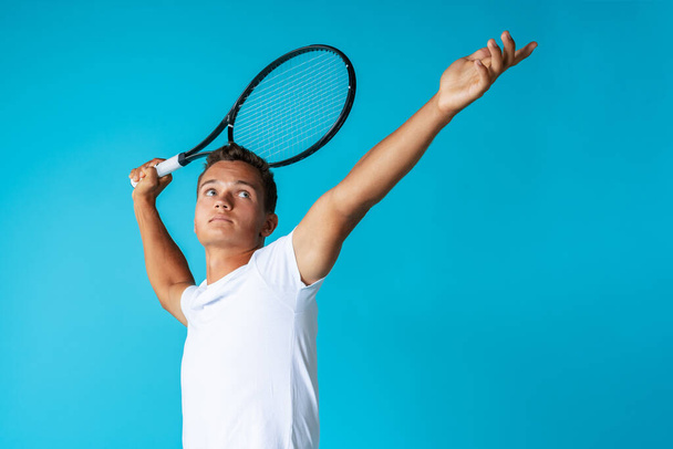 Young man tennis player in sportswear posing against blue background - Fotoğraf, Görsel