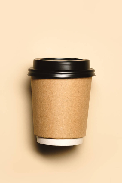 paper cup closeup on a beige background. Recycling craft paper cups of coffee to go. Selective focus. Craft cup for hot beverage, takeaway. Disposable cup. Template for design - Photo, Image