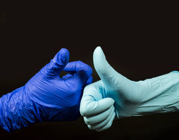 Positief symbool - duimen omhoog. Twee mensen maken dit gebaar in beschermende handschoenen. - Foto, afbeelding
