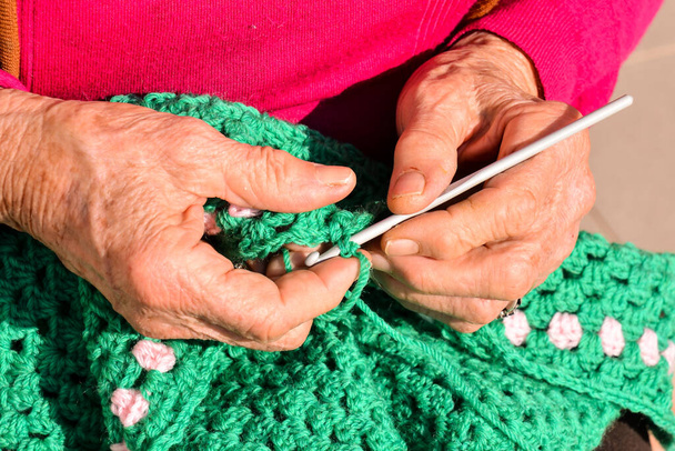 Close-up beeld van een oude vrouw met breinaalden en wol - Foto, afbeelding