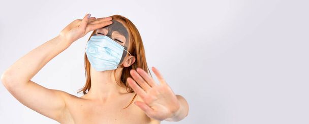 Banner, long format. Tired beautiful girl, in the salon, with a cosmetic mask on her face and another for a pandemic , showing stop virus. Beauty, spa, health and covid 19 concept - Fotoğraf, Görsel