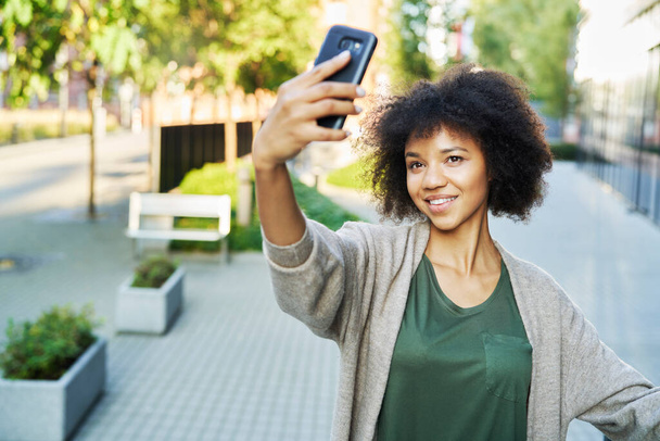 African woman taking a selfie outdoors                                - Photo, Image