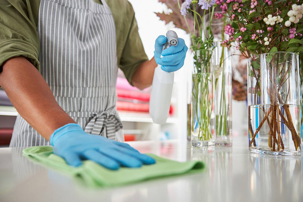 Shop assistant cleaning surfaces in flower shop - Foto, afbeelding