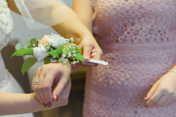 Koszorúslány segít karcsú menyasszony fűzés az esküvői fehér ruhát, gomb finom csipke minta bolyhos szoknya derekán. A reggeli esküvői előkészületek részletei friss házasok. Esküvő napján pillanatok, viselni. - Fotó, kép