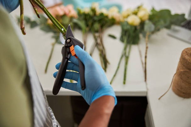Fleuriste utilisant des ciseaux tout en faisant bouquet au travail - Photo, image
