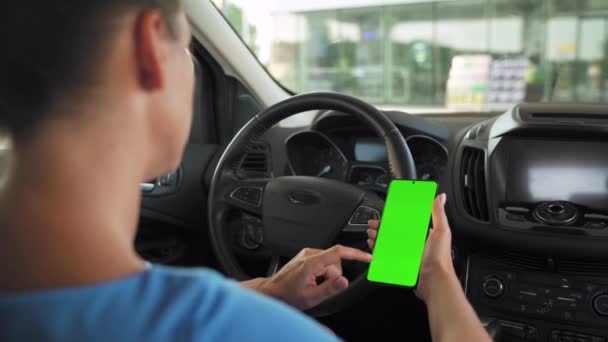Egy női sofőr okostelefont használ az autóban. Chromakey okostelefon zöld képernyővel. Automata navigáció. Internetfüggőség - Felvétel, videó