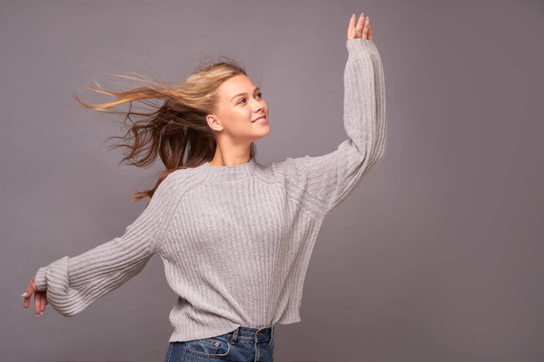 Close-up of a girl in flying motion in gray clothes on a gray background - Fotografie, Obrázek