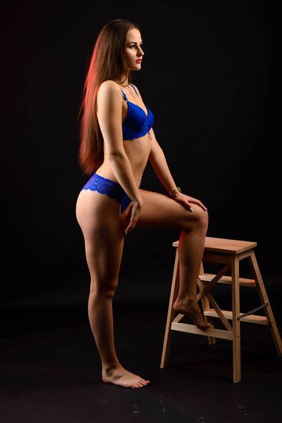 Fashion brunette vrouw met lang donker haar in blauwe lingerie, geïsoleerd op donkergrijze achtergrond - Foto, afbeelding