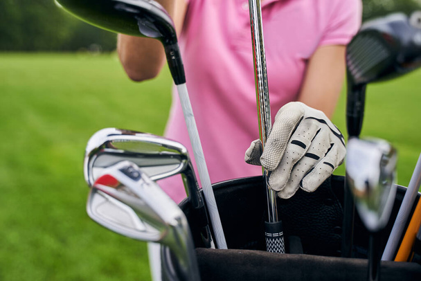 Female player choosing clubs for the game of golf - Foto, Imagen