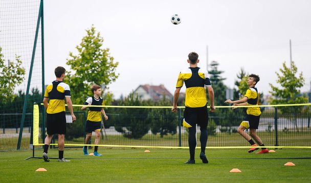 Молоді футболісти-підлітки грають у теніс на тренувальному майданчику. Підлітки займаються футболом на траві. Молоді хлопчики займаються спортом
 - Фото, зображення