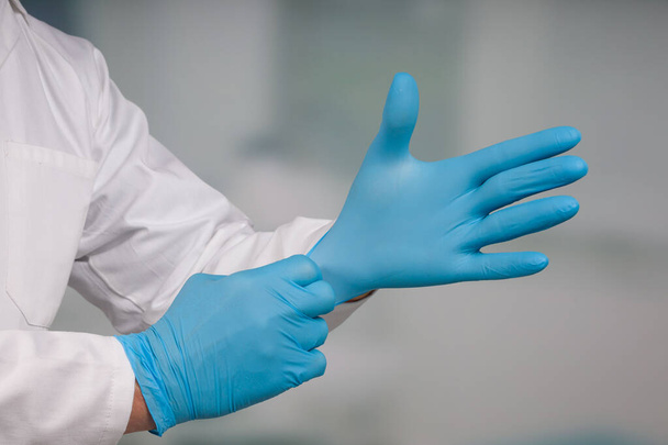 Закрыть руки, надевая медицинские перчатки  - Фото, изображение