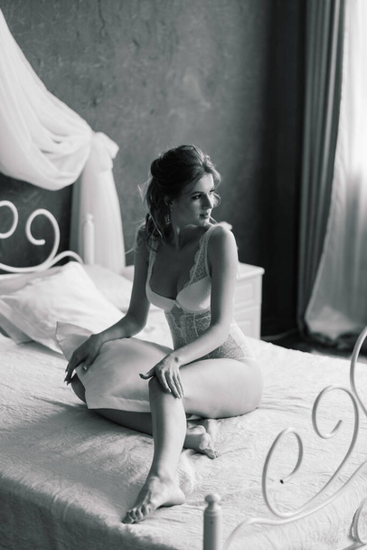 Kaunis seksikäs morsian valkoisissa alusvaatteissa makaa sängyllä makuuhuoneessaan - Valokuva, kuva