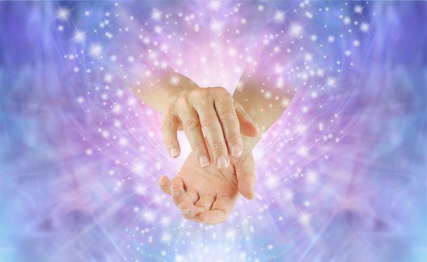 Spirituális gyógyító energia küldése az éteren keresztül neked - női gyógyító összecsukott kézzel, kék rózsaszín csillogó éteri háttérrel - Fotó, kép