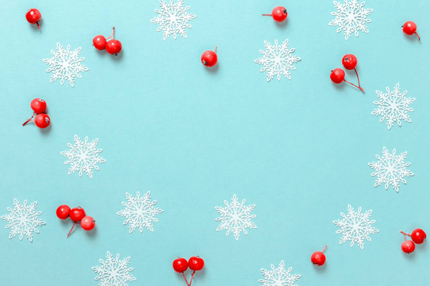 Рождественская распродажа Красная ягода, белые снежинки в форме рамки на пастельно-голубом фоне для поздравительной открытки. Xmas backdrop with space for text - Фото, изображение