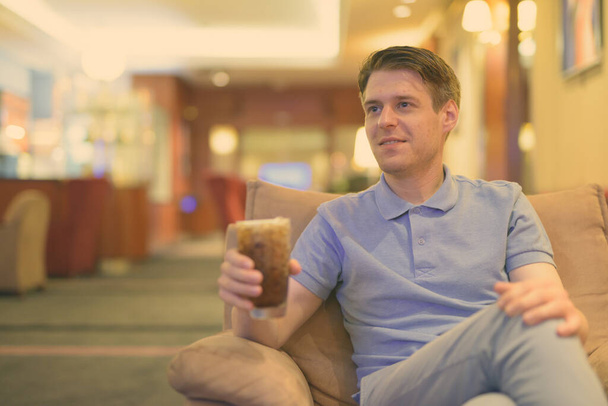 Mladý pohledný muž relaxuje v hotelové hale - Fotografie, Obrázek